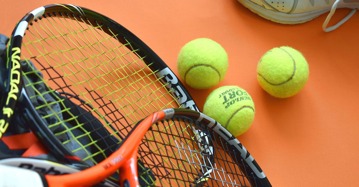 Raquette de tennis et balles de tennis posées sur un terrain en terre battue