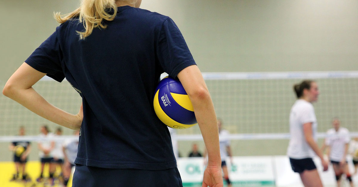 Une joueuse de volleyball de dos avec un ballon sous le bras