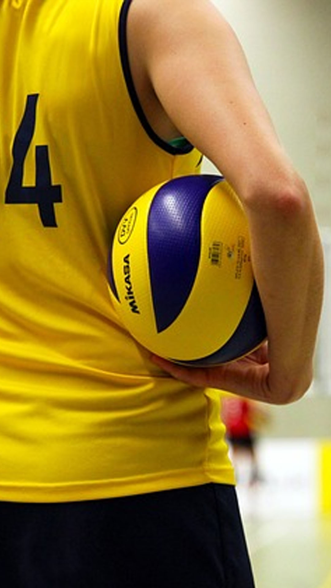 Jeune femme qui joue au volley de dos avec un ballon sous le bras
